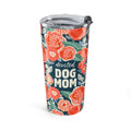 A tall insulated tumbler with a clear lid and black straw, decorated with a coral and green floral pattern on a dark navy background and the words 'devoted DOG MOM' in white text.