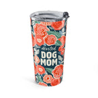 A tall insulated tumbler with a clear lid and black straw, decorated with a coral and green floral pattern on a dark navy background and the words 'devoted DOG MOM' in white text.