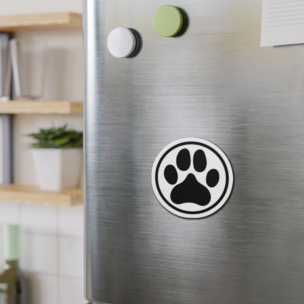 Black-and-white dog paw print die-cut magnet with a circular border, shown on a refrigerator door – Kate Spain design