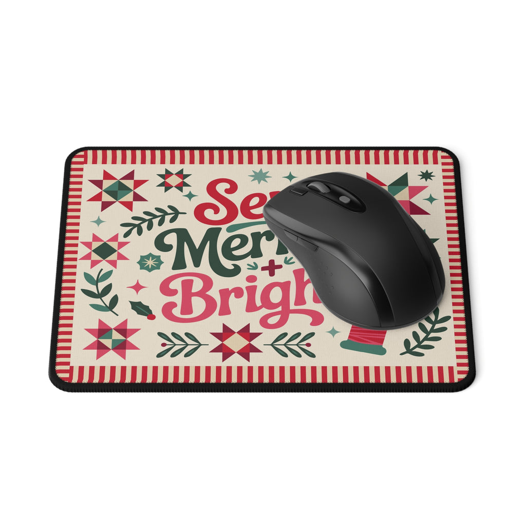 Sew Merry + Bright lettering mouse pad with quilt-block stars and holly, with a computer mouse – Kate Spain design for Pat Sloan