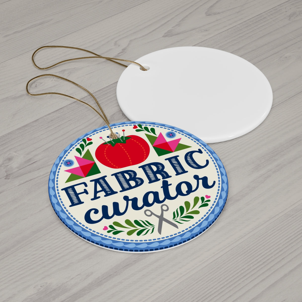 Fabric Curator round porcelain Christmas ornament, front and blank back on a table – Kate Spain design for Pat Sloan