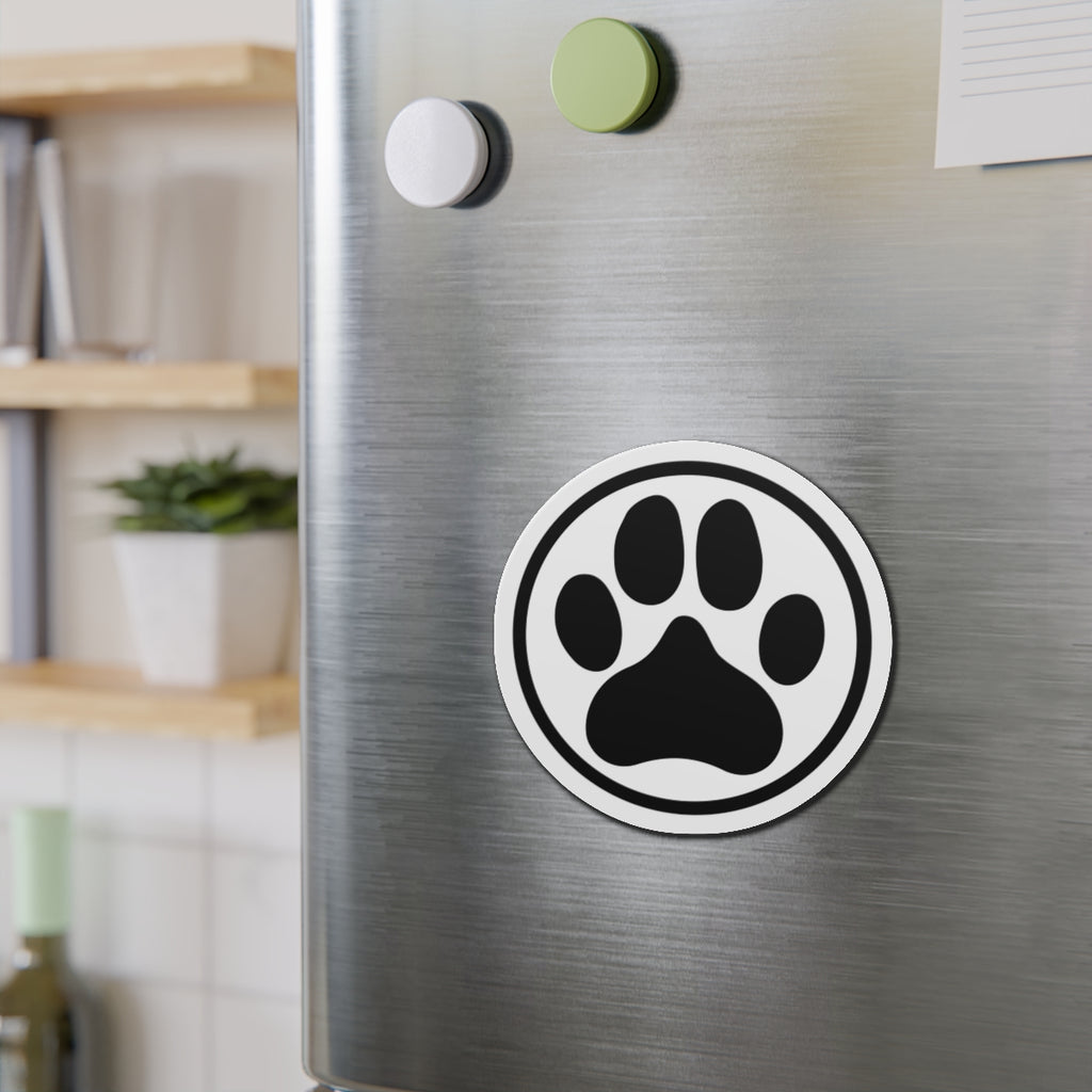 Black-and-white dog paw print die-cut magnet with a circular border, shown on a refrigerator door – Kate Spain design