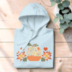 Falling for Fall patchwork pumpkin with quilt-block stars and hearts on a pullover hoodie in sky blue, folded and styled on wood with eucalyptus – Kate Spain design for Pat Sloan