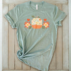 Falling for Fall patchwork pumpkin with quilt-block stars and hearts on a t-shirt in sage, styled on wood – Kate Spain design for Pat Sloan