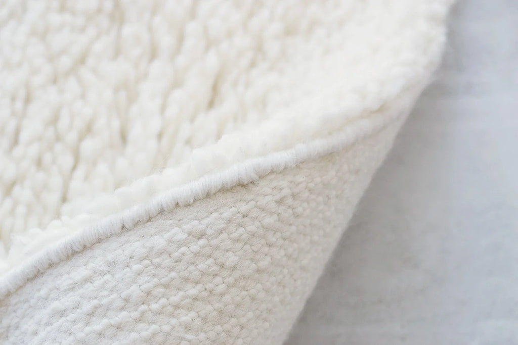 nothing to hide hand-knotted shag throw rug in undyed natural white New Zealand wool, corner turned up to show the back – Kate Spain design
