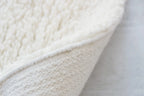 nothing to hide hand-knotted shag throw rug in undyed natural white New Zealand wool, corner turned up to show the back – Kate Spain design