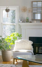 nothing to hide hand-knotted shag throw rug in undyed natural white New Zealand wool, draped over an armchair by a fireplace – Kate Spain design
