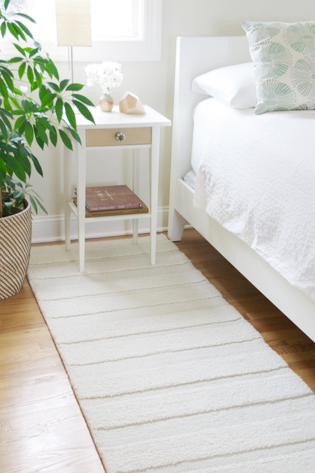 eye heart hand Pure Stripe hand-tufted rug in undyed natural white wool with subtle tonal stripes, beside a bed in a white bedroom – Kate Spain design