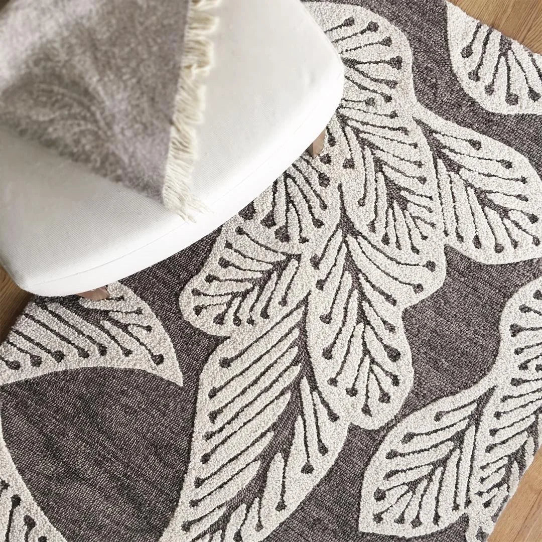 eye heart hand Taupe Leaf hand-tufted wool rug with oversized cream leaves on taupe, close-up beneath a white chair – Kate Spain design