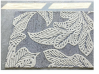 eye heart hand Grey Leaf hand-tufted wool rug with oversized cream leaves on grey, on a concrete floor, angled view – Kate Spain design