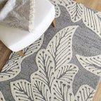 eye heart hand Grey Leaf hand-tufted wool rug with oversized cream leaves on grey, close-up beneath a white chair – Kate Spain design