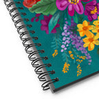 Posy spiral notebook with a painterly bouquet of magenta, yellow, pink and red flowers on deep teal, close-up of the spiral binding – Kate Spain design