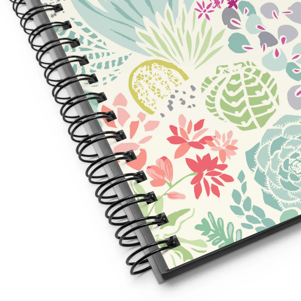 Desert spiral notebook with pale green succulents and cacti with coral and magenta blooms on cream, close-up of the spiral binding – Kate Spain design