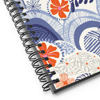 Hills + Valleys spiral notebook with layered periwinkle hills dotted with orange, coral and pink flowers on cream, close-up of the spiral binding – Kate Spain design