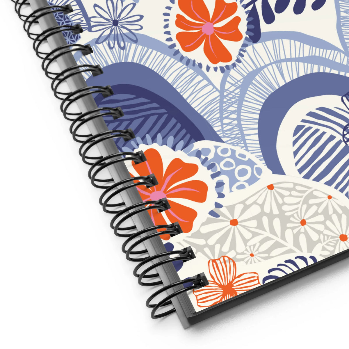 Hills + Valleys spiral notebook with layered periwinkle hills dotted with orange, coral and pink flowers on cream, close-up of the spiral binding – Kate Spain design