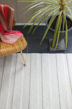 eye heart hand Pure Stripe hand-tufted rug in undyed natural white wool with subtle tonal stripes, beneath a molded plywood chair and potted palm – Kate Spain design