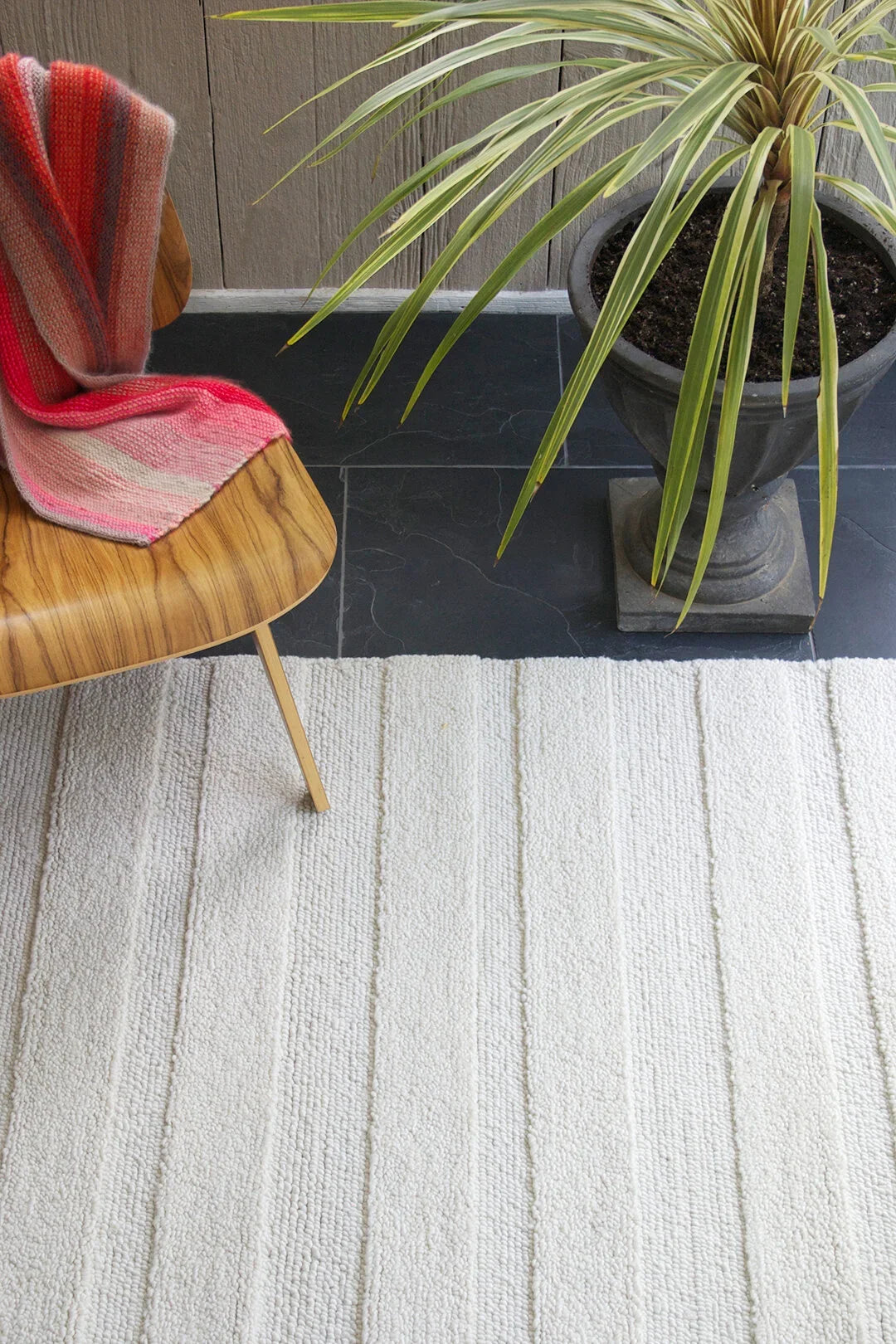 eye heart hand Pure Stripe hand-tufted rug in undyed natural white wool with subtle tonal stripes, beneath a molded plywood chair and potted palm – Kate Spain design