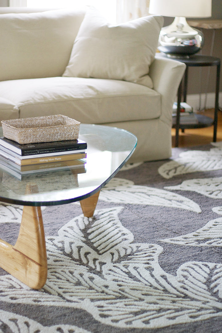 eye heart hand® Taupe Leaf rug under a glass coffee table in a living room