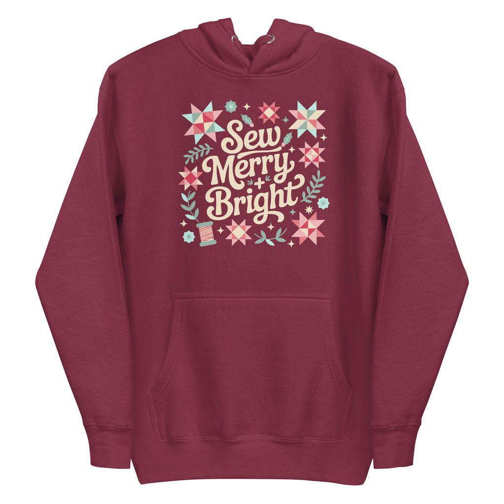 Sew Merry + Bright lettering with quilt-block stars, holly and a thread spool on a pullover hoodie in maroon, front view – Kate Spain design for Pat Sloan