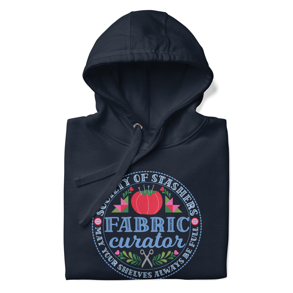 Fabric Curator Society of Stashers badge with a tomato pincushion on a pullover hoodie in navy, folded close-up of the design – Kate Spain design for Pat Sloan