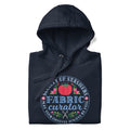 Fabric Curator Society of Stashers badge with a tomato pincushion on a pullover hoodie in navy, folded close-up of the design – Kate Spain design for Pat Sloan