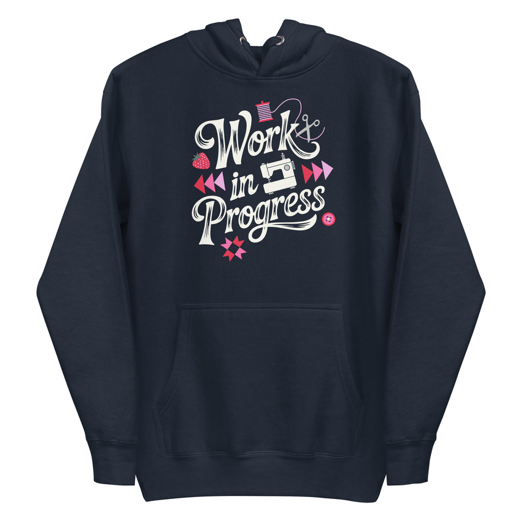 Work in Progress sewing design with flying geese, sewing machine, strawberry and thread spool on a pullover hoodie in navy, front view – Kate Spain design for Pat Sloan