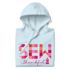 Sew Thankful patchwork lettering with a heart-topped thread spool on a pullover hoodie in sky blue, folded close-up of the design – Kate Spain design for Pat Sloan