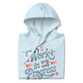 Work in Progress sewing design with flying geese, sewing machine, strawberry and thread spool on a pullover hoodie in sky blue, folded close-up of the design – Kate Spain design for Pat Sloan