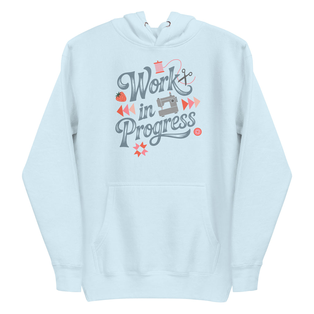 Work in Progress sewing design with flying geese, sewing machine, strawberry and thread spool on a pullover hoodie in sky blue, front view – Kate Spain design for Pat Sloan