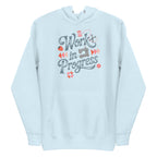 Work in Progress sewing design with flying geese, sewing machine, strawberry and thread spool on a pullover hoodie in sky blue, front view – Kate Spain design for Pat Sloan