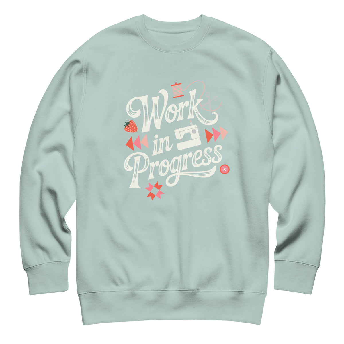 Work in Progress script lettering with sewing icons on a premium sweatshirt in agave, front view – Kate Spain design for Pat Sloan
