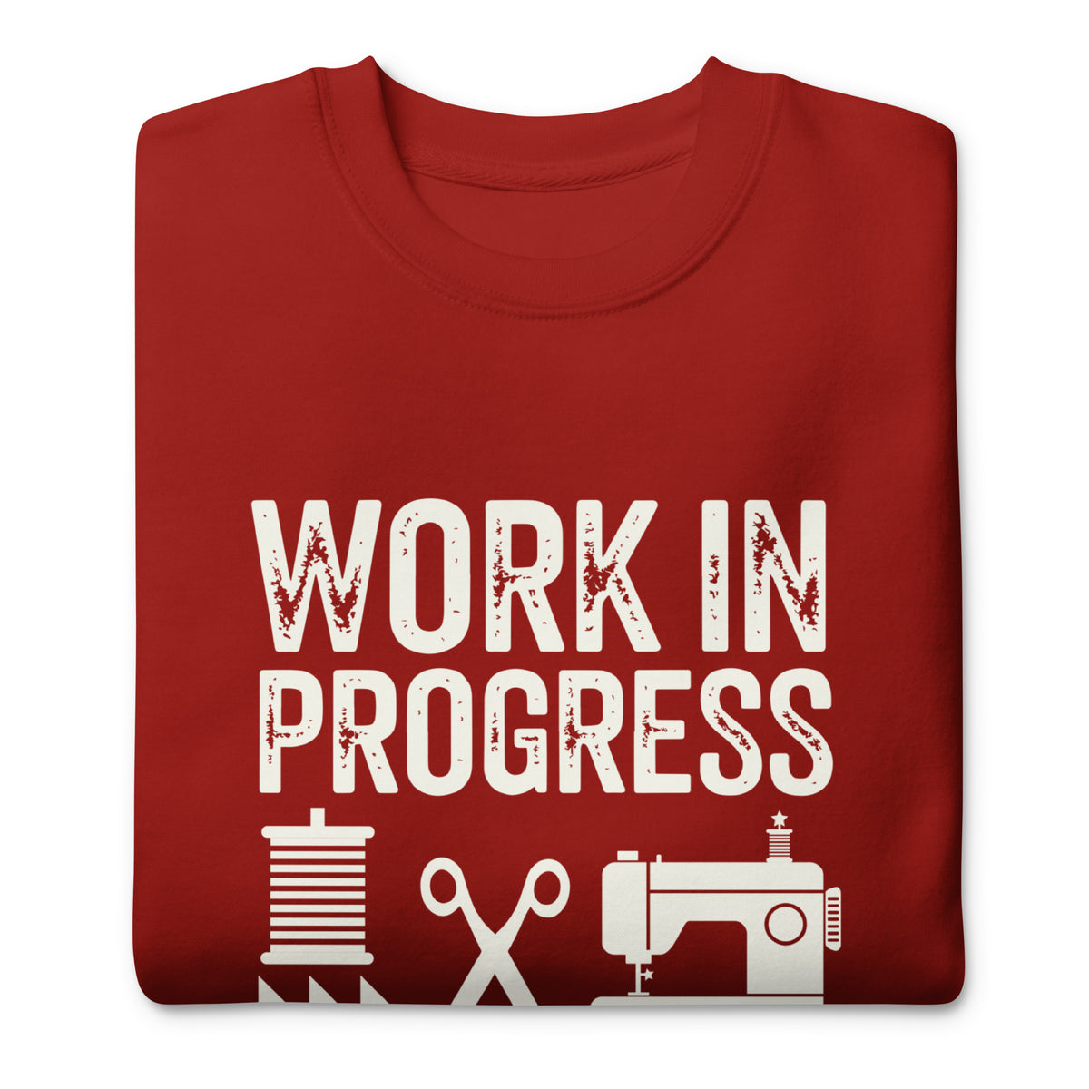 Work in Progress lettering with sewing icons on a premium sweatshirt in cardinal red, folded close-up of the design – Kate Spain design for Pat Sloan