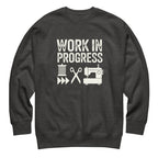 Work in Progress lettering with sewing icons on a premium sweatshirt in charcoal grey, front view – Kate Spain design for Pat Sloan