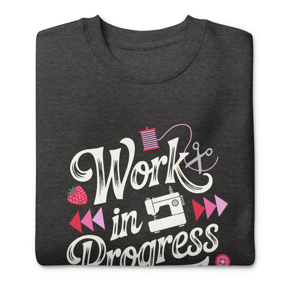 Work in Progress script lettering with sewing icons on a premium sweatshirt in charcoal grey, folded close-up of the design – Kate Spain design for Pat Sloan