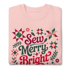 Sew Merry + Bright lettering with quilt stars and holly on a premium sweatshirt in pink, folded close-up of the design – Kate Spain design for Pat Sloan