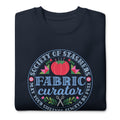 Fabric Curator Society of Stashers badge with a tomato pincushion on a crewneck sweatshirt in navy, folded close-up of the design – Kate Spain design for Pat Sloan