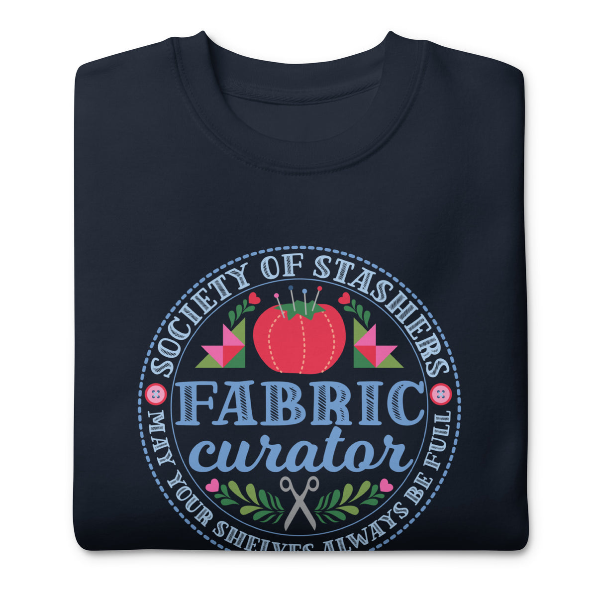 Fabric Curator Society of Stashers badge with a tomato pincushion on a crewneck sweatshirt in navy, folded close-up of the design – Kate Spain design for Pat Sloan