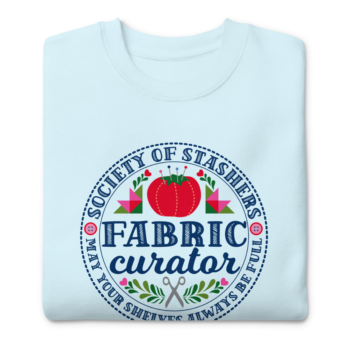 Fabric Curator Society of Stashers badge with a tomato pincushion on a crewneck sweatshirt in sky blue, folded close-up of the design – Kate Spain design for Pat Sloan