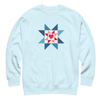 Liberty Love star quilt block with a heart in red, white and blue on a crewneck sweatshirt in sky blue, front view – Kate Spain design for Pat Sloan