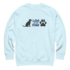 Law of the Paw® logo with seated dog and paw print on a crewneck sweatshirt in sky blue, front view – Kate Spain design