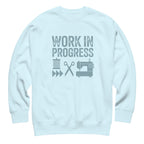Work in Progress lettering with sewing icons on a premium sweatshirt in sky blue, front view – Kate Spain design for Pat Sloan