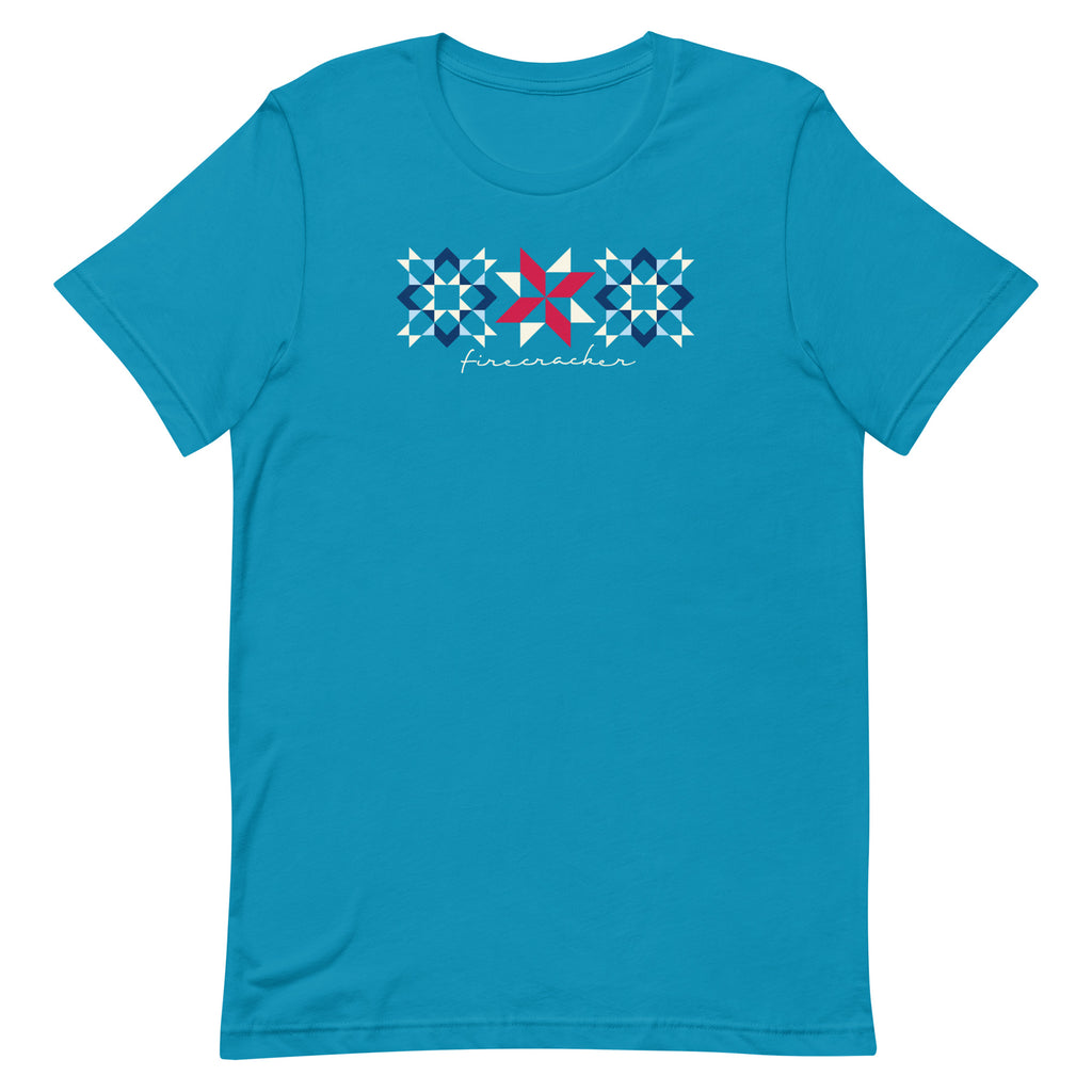 Firecracker quilt-block stars with script lettering in red, white and blue on a t-shirt in aqua, front view – Kate Spain design for Pat Sloan