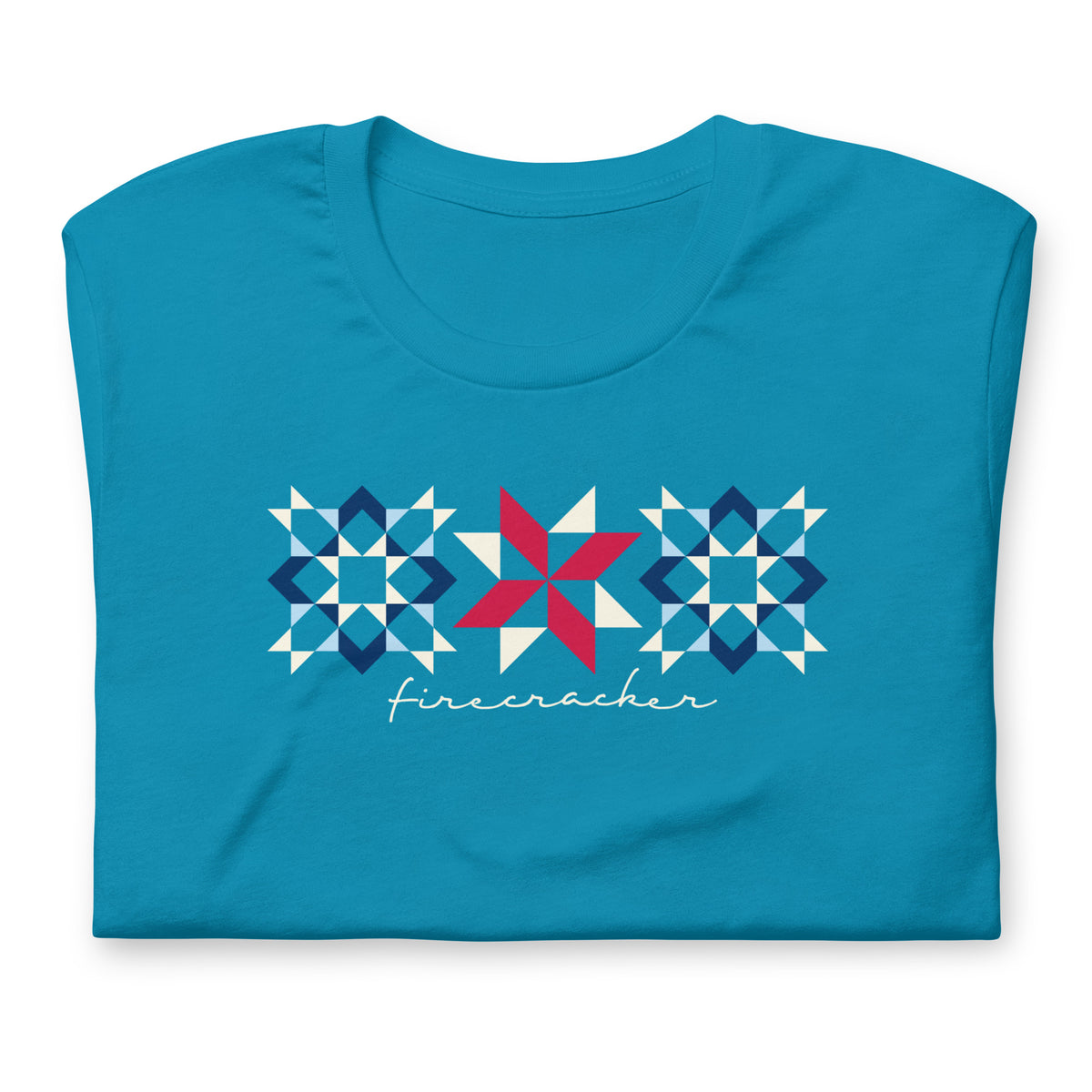 Firecracker quilt-block stars with script lettering in red, white and blue on a t-shirt in aqua, folded close-up of the design – Kate Spain design for Pat Sloan