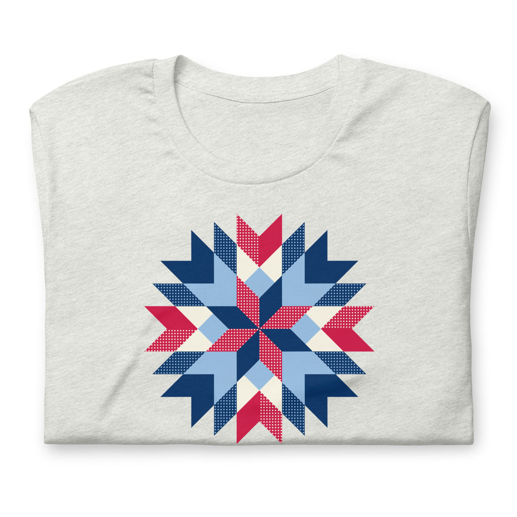 Barn Star quilt block in red, white and blue on a t-shirt in ash, folded close-up of the design – Kate Spain design for Pat Sloan