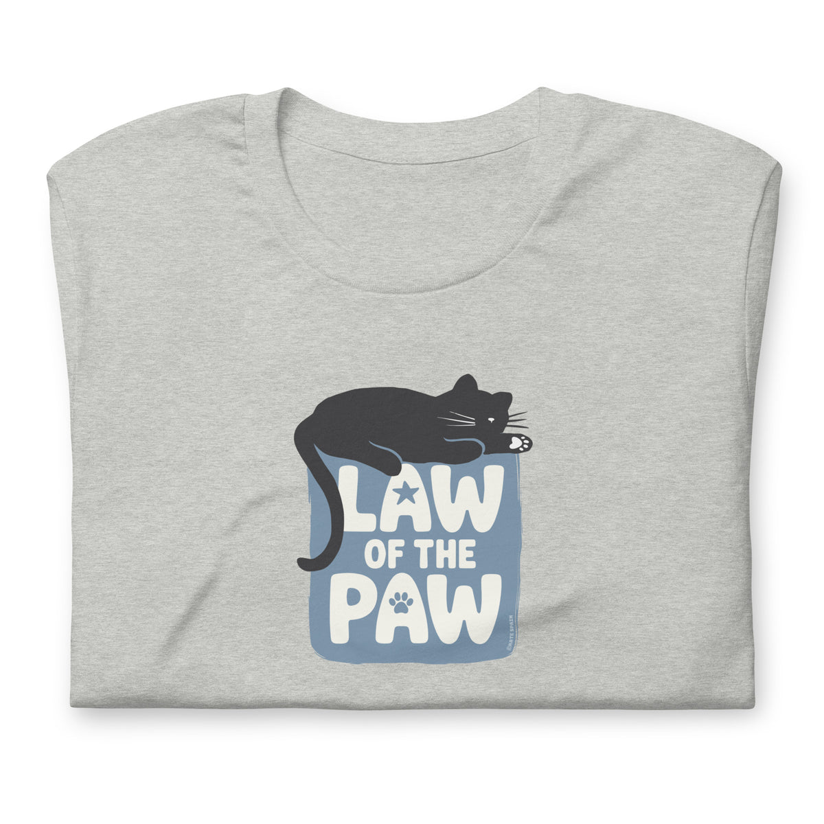 Law of the Paw® design with a cat napping on the logo on a t-shirt in athletic heather grey, folded close-up of the design – Kate Spain design