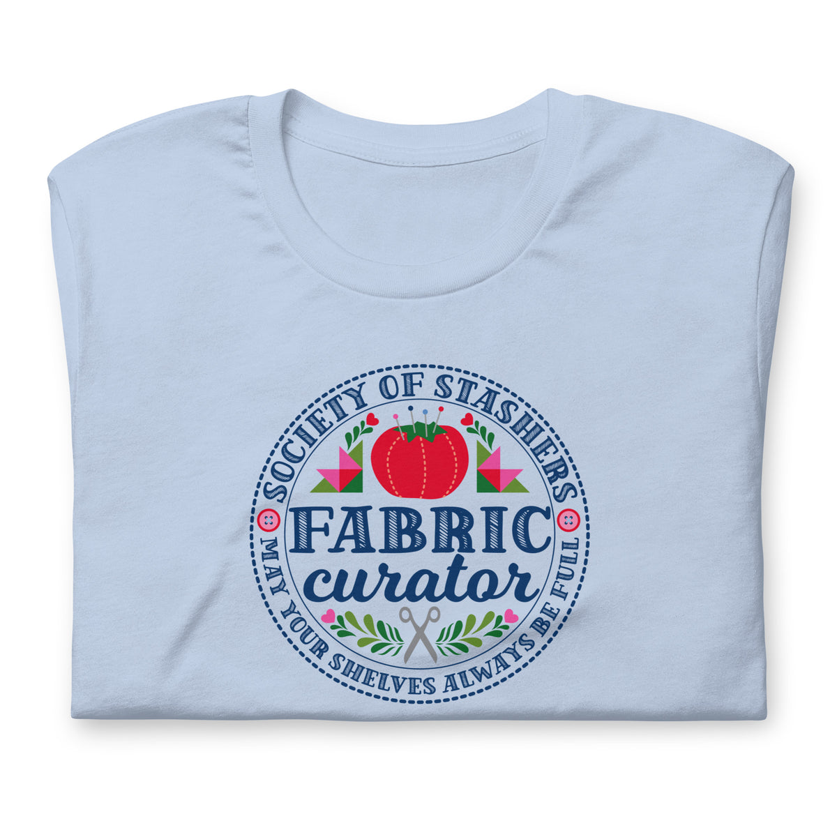 Fabric Curator Society of Stashers badge with a tomato pincushion on a t-shirt in light blue, folded close-up of the design – Kate Spain design for Pat Sloan