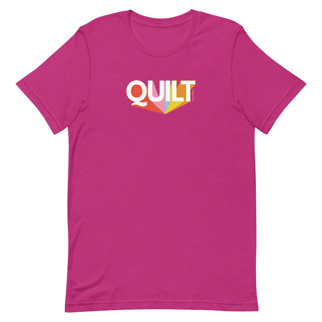 Moda QUILT logo with orange, pink, blue and yellow rays on a staple t-shirt in berry, front view – Kate Spain design