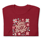 Sew Merry + Bright lettering with quilt stars and holly on a staple t-shirt in cardinal red, folded close-up of the design – Kate Spain design for Pat Sloan