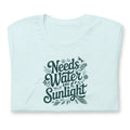 Needs Water + Sunlight hand lettering with leaf and sun accents on a t-shirt in heather ice blue, folded close-up of the design – Kate Spain design
