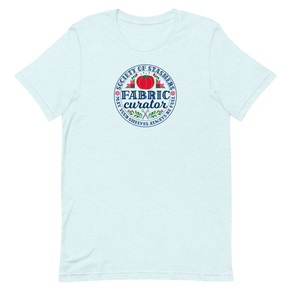 Fabric Curator Society of Stashers badge with a tomato pincushion on a t-shirt in heather ice blue, front view – Kate Spain design for Pat Sloan
